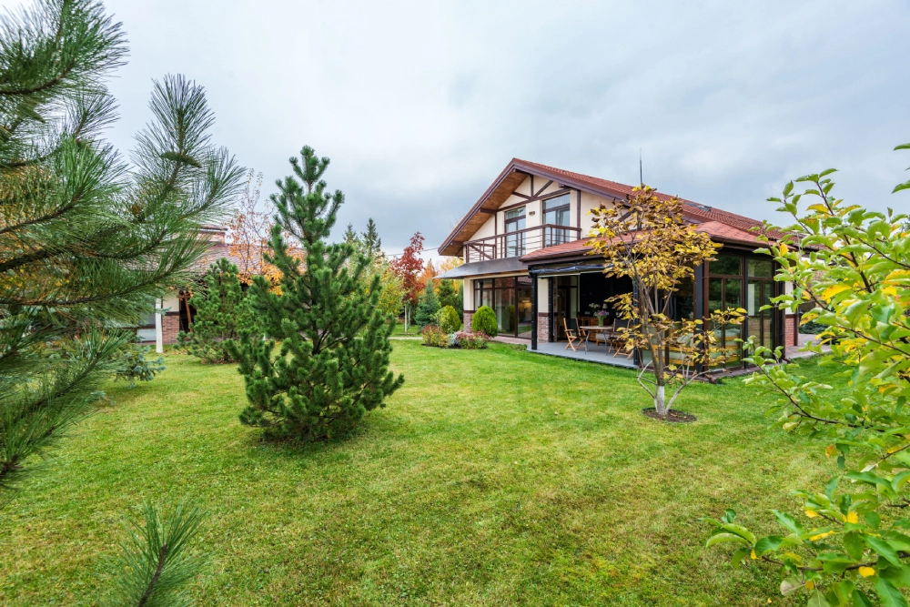 Maintained backyard lawn and garden with established trees surrounding a residential home.