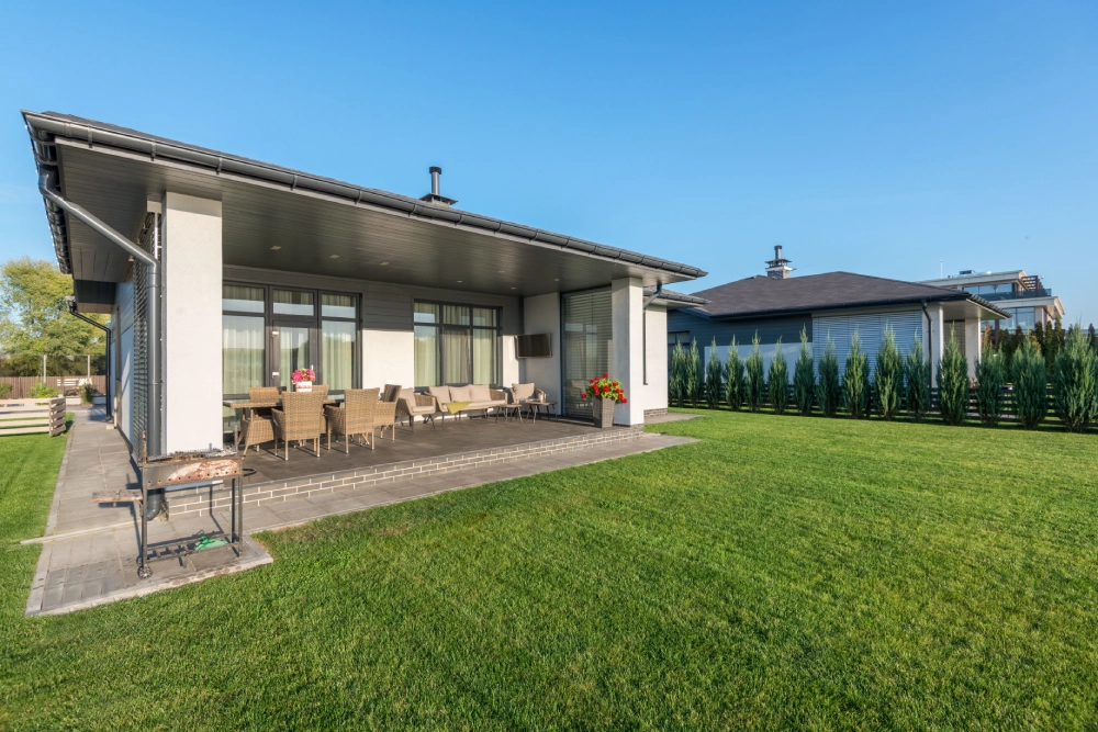 Freshly maintained backyard lawn beside a modern home and outdoor entertaining area.
