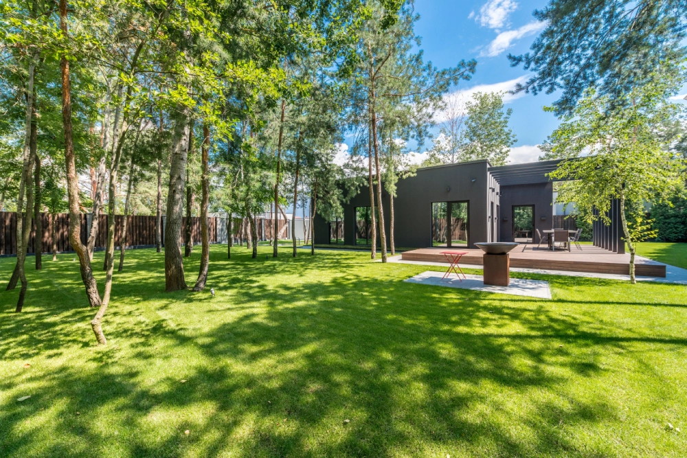 Maintained lawn with established trees surrounding a modern residential home.