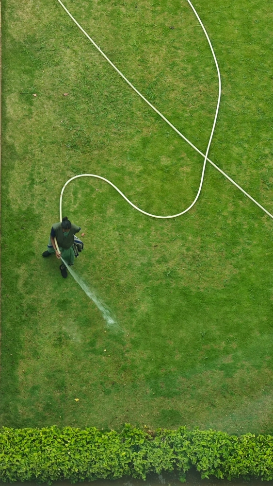 Lawn care professional watering a large grass lawn.