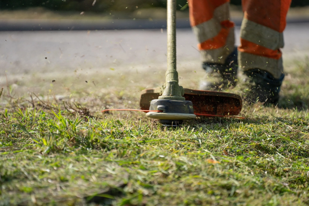 Lawn care worker trimming grass edges with a line trimmer.